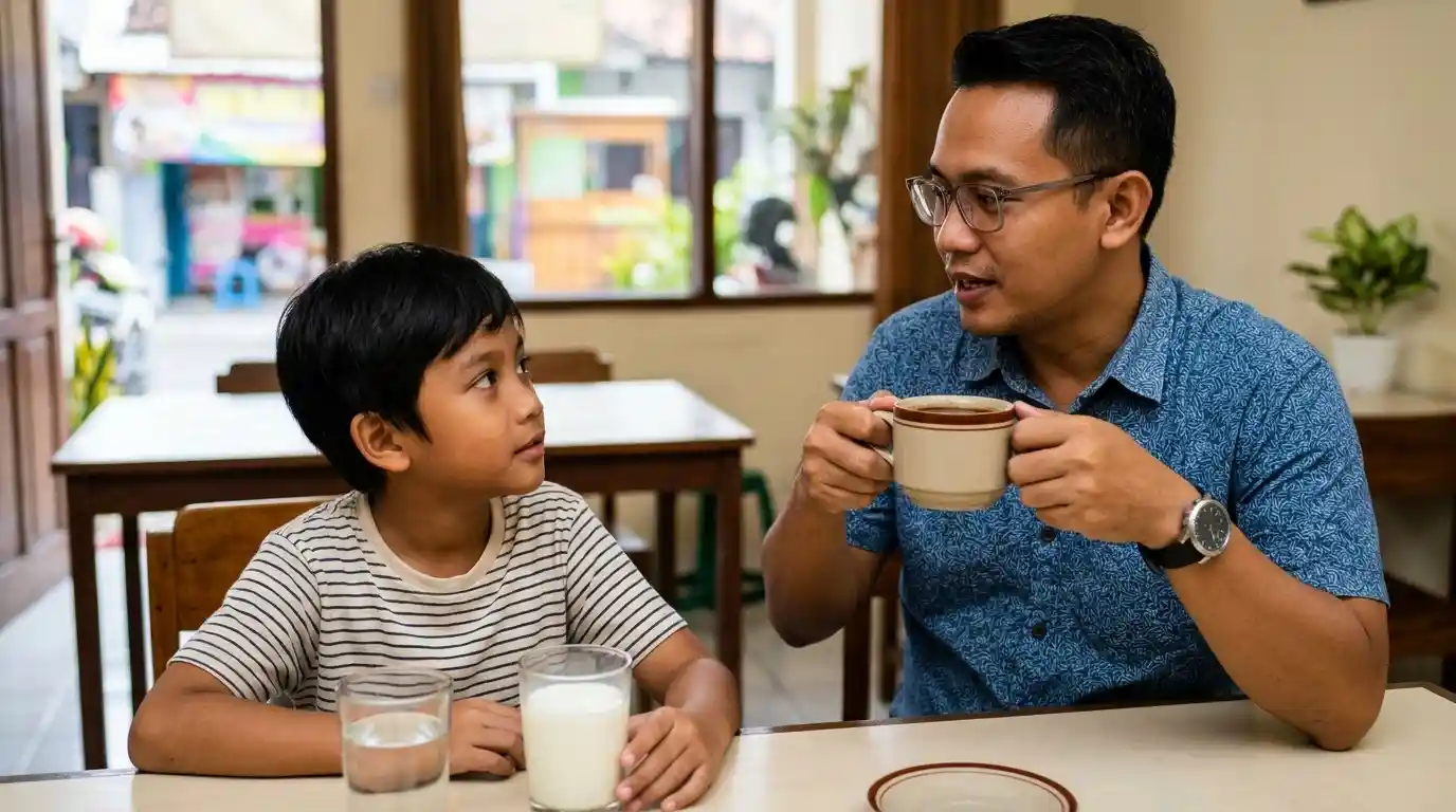 Ayah dan anak memegang cangkir minuman di meja makan.